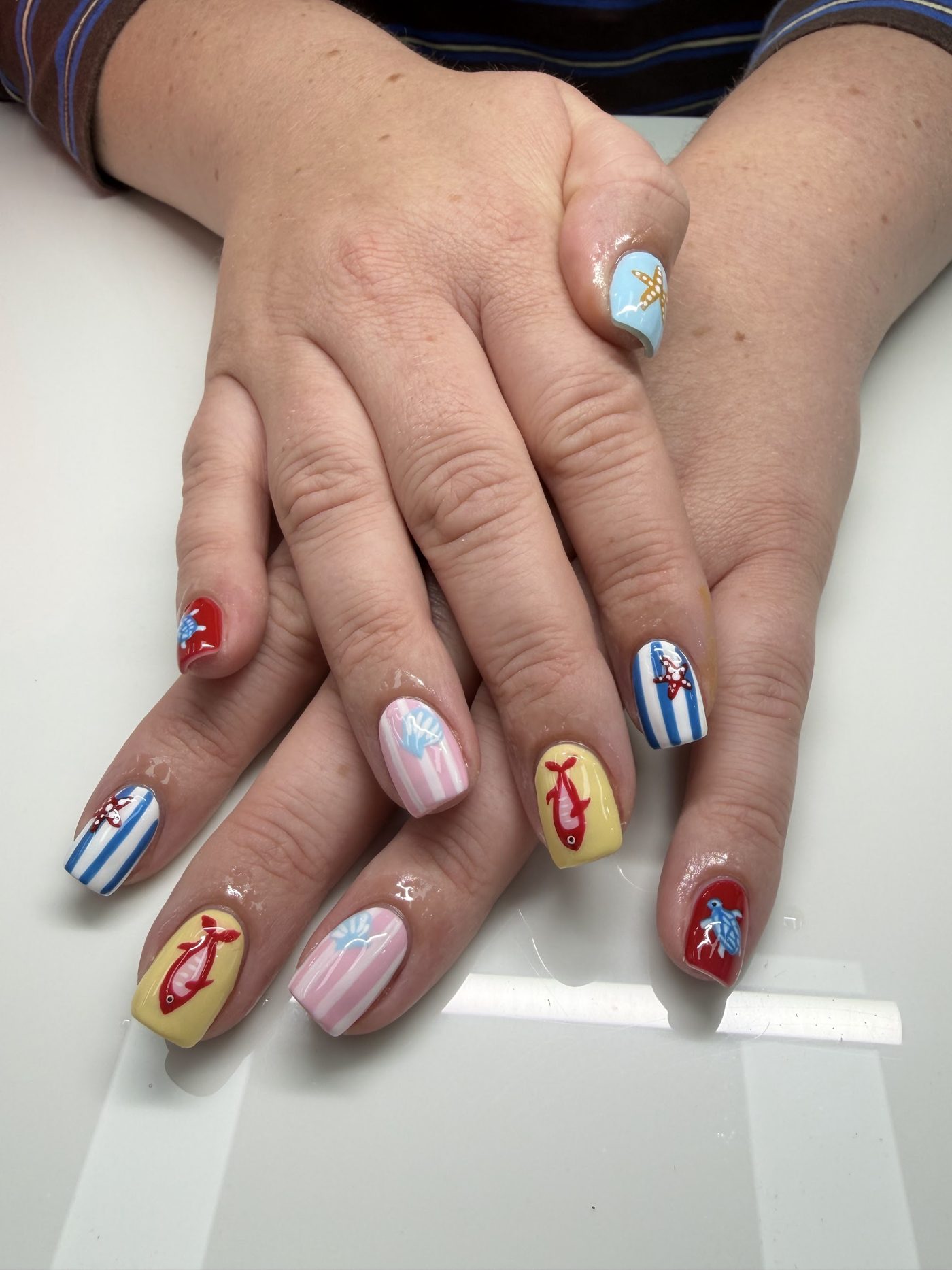Ocean-themed nail art with hand-painted fish, starfish and shells
