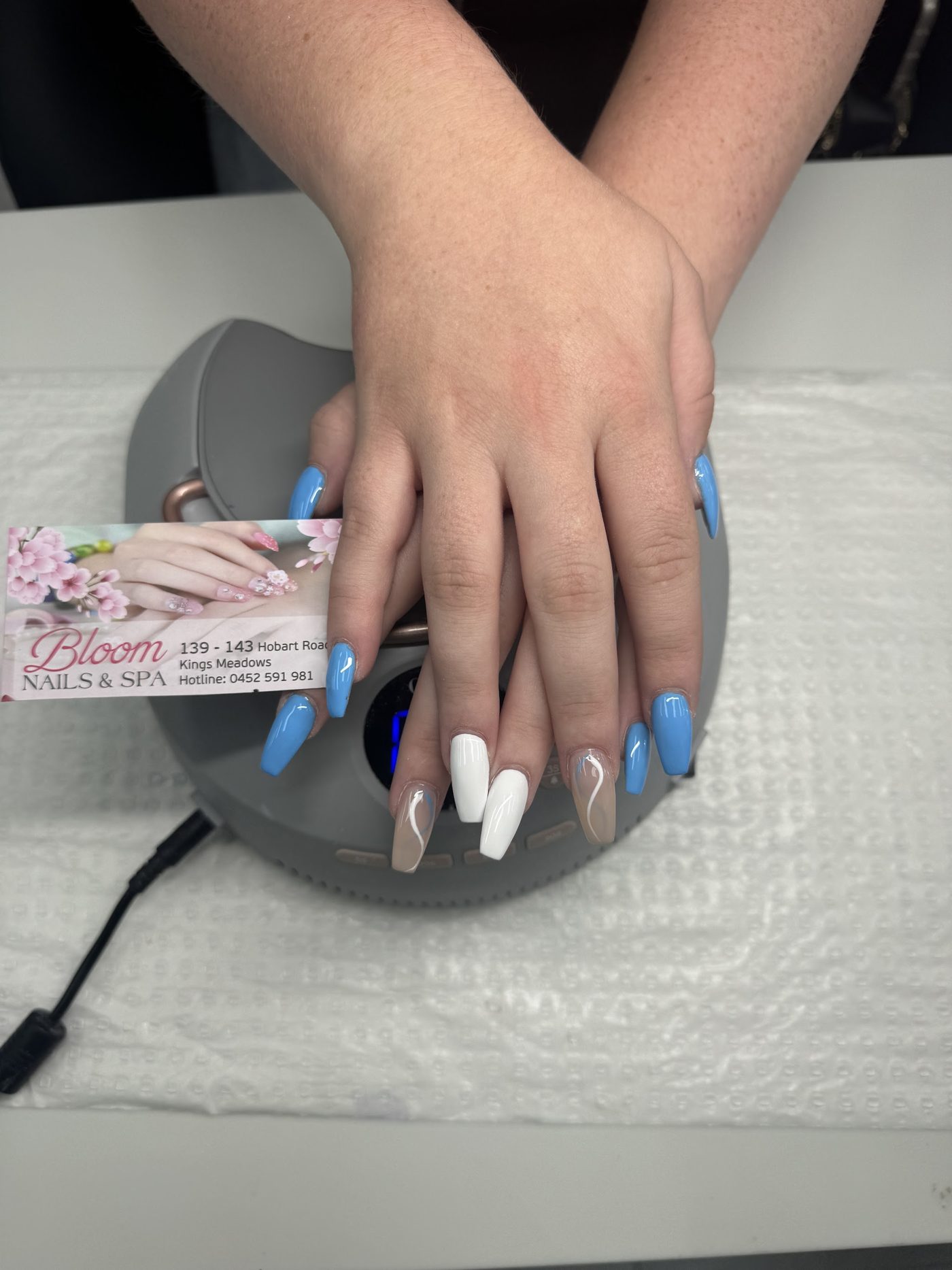Sky blue, white and nude long nails under the UV lamp